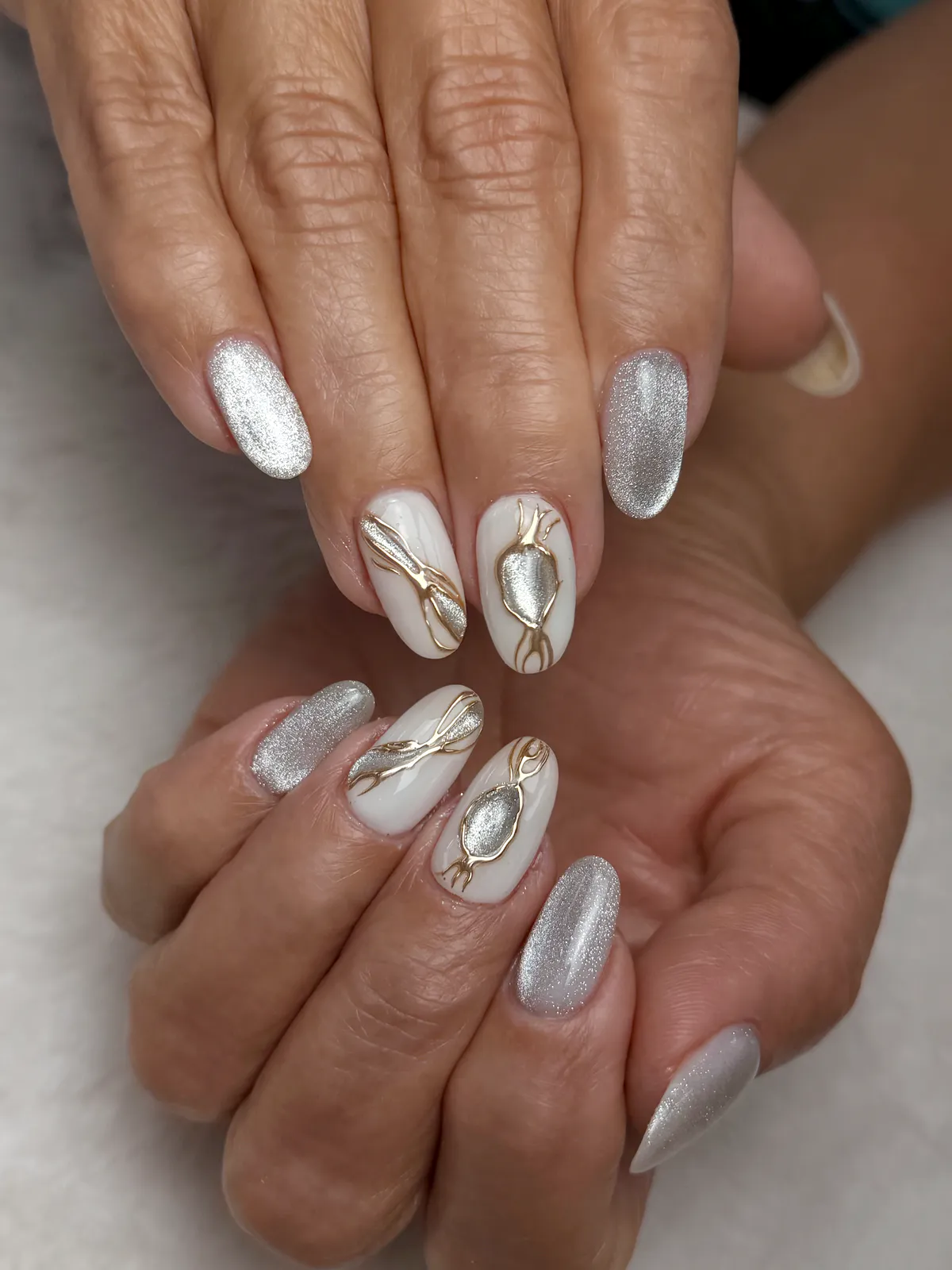 Almond nails in silver velvet chrome with white accents and gold lines, by BeautyFusionClau in Sarasota, Florida